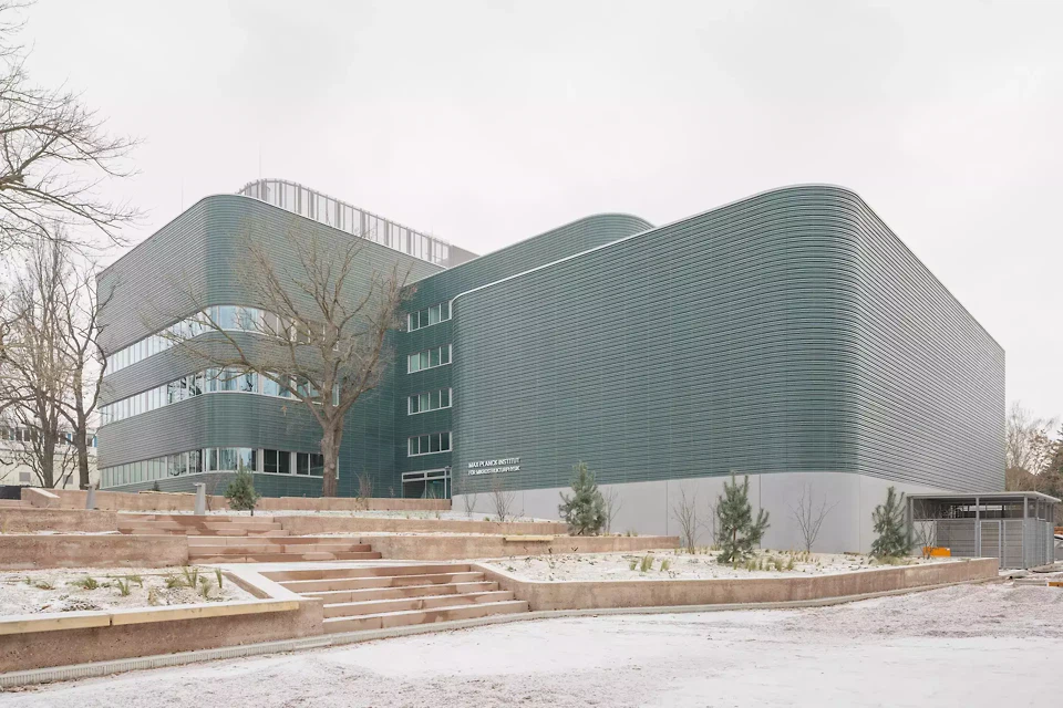 Drei gestaffelte Baukörper fügen Labore, Büros und Reinraum zu einem funktionalen Ensemble, das auf Topografie und Campus reagiert.