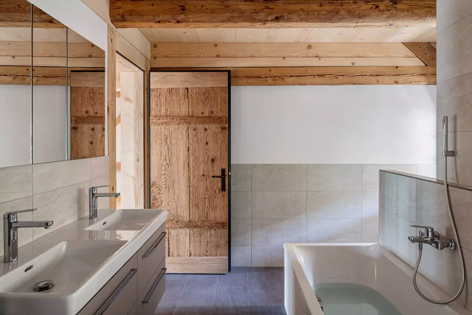 Badezimmer mit historischer Brettertür und freiliegender Balkendecke.