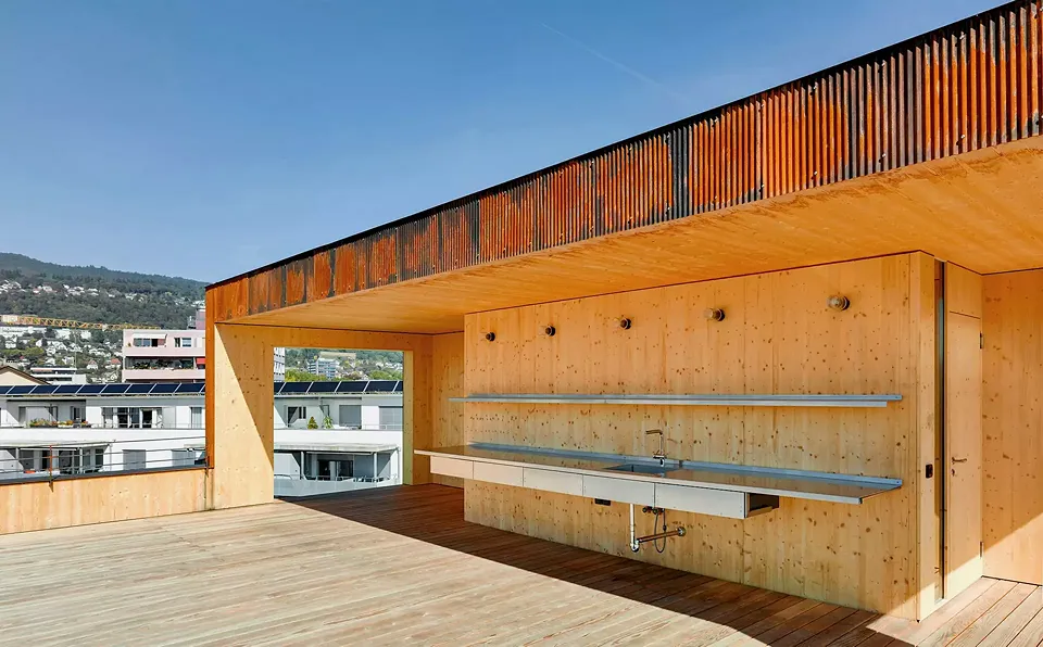 Auf dem Dach gibt es eine Gemeinschafts-Terrasse. Dieser Ort bietet nicht  nur einen herrlichen Blick  auf die Stadt, sondern  auch eine Außen- und Gemeinschaftsküche,  die durch ein Vordach geschützt ist.