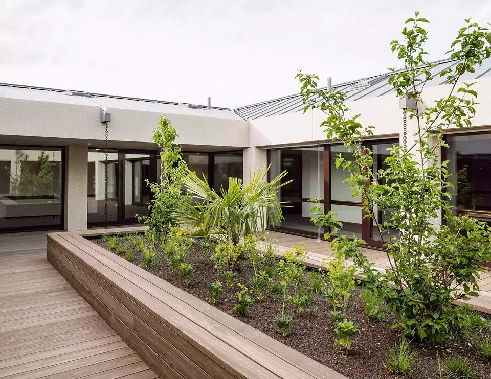 Im Obergeschoss bieten eine Dachterrasse aus Holz und  eine Gartengestaltung den Kurzzeitbewohnern einen  Bereich zum Verweilen.