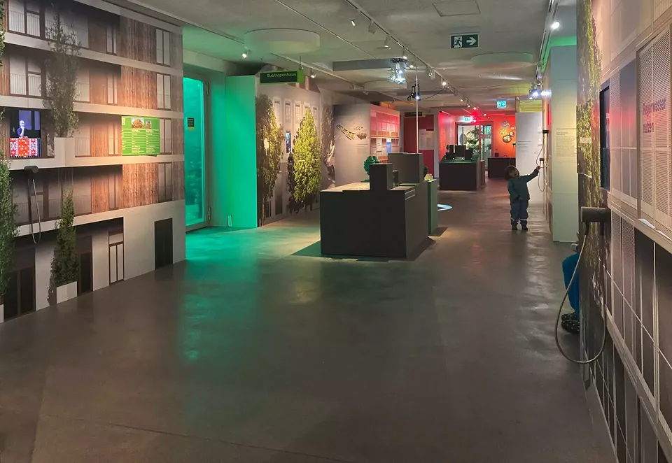 Blick in die Strassenflucht von dem in kühleres Licht getauchten Teil der Ausstellung in Richtung Hitzeraum.