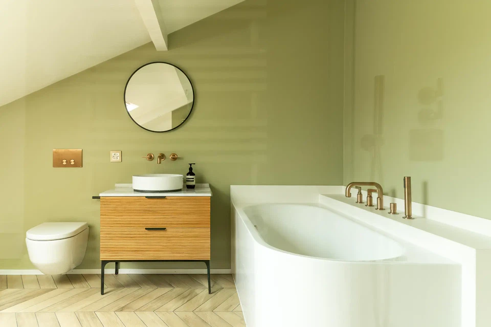 Badezimmer unter dem Dach mit Holz, mineralischen Oberflächen und Messingarmaturen