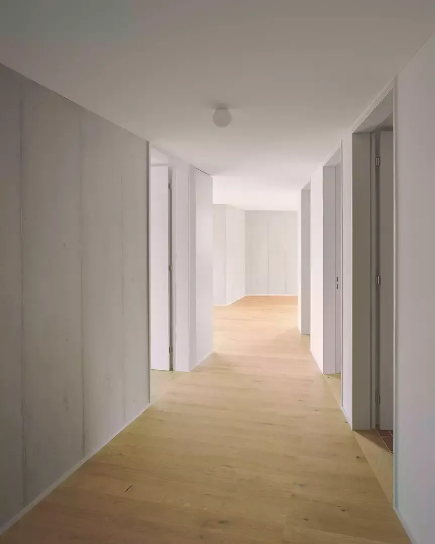 Raumhohe Türen lösen die Wände in Scheiben auf. Diese sind als Sichtbeton,  gestrichenes oder verputztes Mauerwerk ausgeführt.
