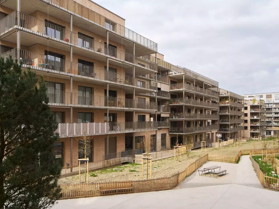 La façade sud s’ouvre généreusement sur le grand pré central : les balcons-coursives deviennent des lieux de vie prolongés, animés par les aménagements des coopérateurs et en dialogue direct avec les espaces communs végétalisés.