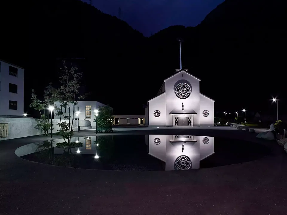 Überlagerungen. Zahlreiche für das Unterwallis charakteristische und landschaftsprägende Elemente: ein Teich, einige Erlen, der Berg, eine Mauer, eine Kirche und ein Relief mit drei Heiligen.