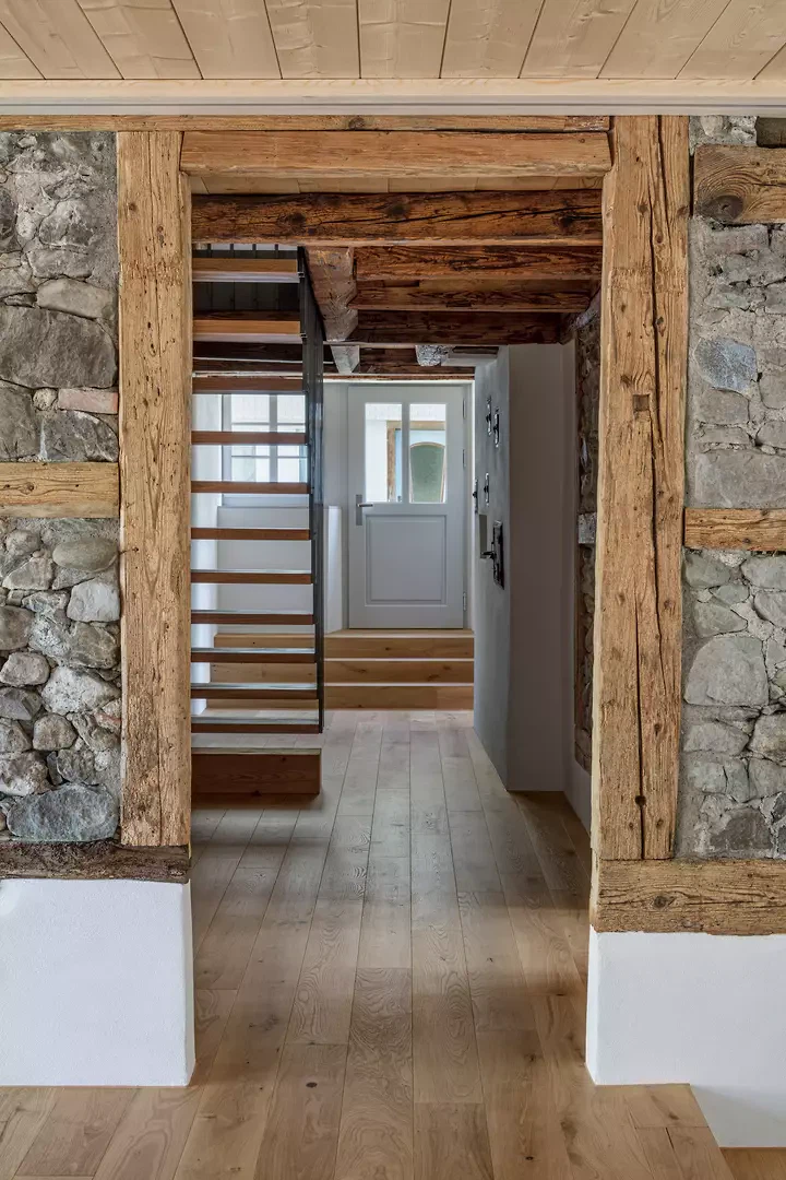 Wanddurchbruch durch den zentralen Mittelgang mit neuer Stahltreppe und historischer Eingangstür.