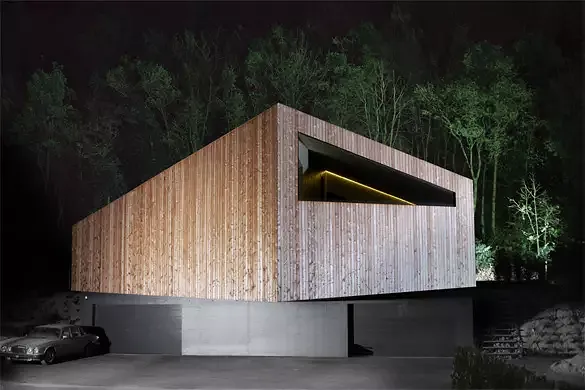 Vue nord: le volume en bois du logement se distingue clairement des garages en béton au niveau de la route