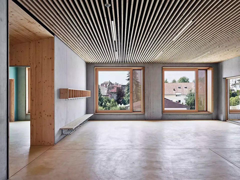 L’installation technique et les éléments acoustiques sont intégrés dans le plafond nervuré en béton ainsi que dans le plafond à lamelles en bois, ce qui contribue à une apparence homogène.