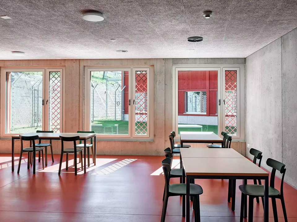 Der Aufenthalts- und Essbereich des Wohntrakts mit Blick auf den trapez- förmigen, zugänglichen Hof nach Nordosten. Die Gitter  vor den Fensterflügeln  spielen mit dem Motiv des ländlichen Spaliergitters.