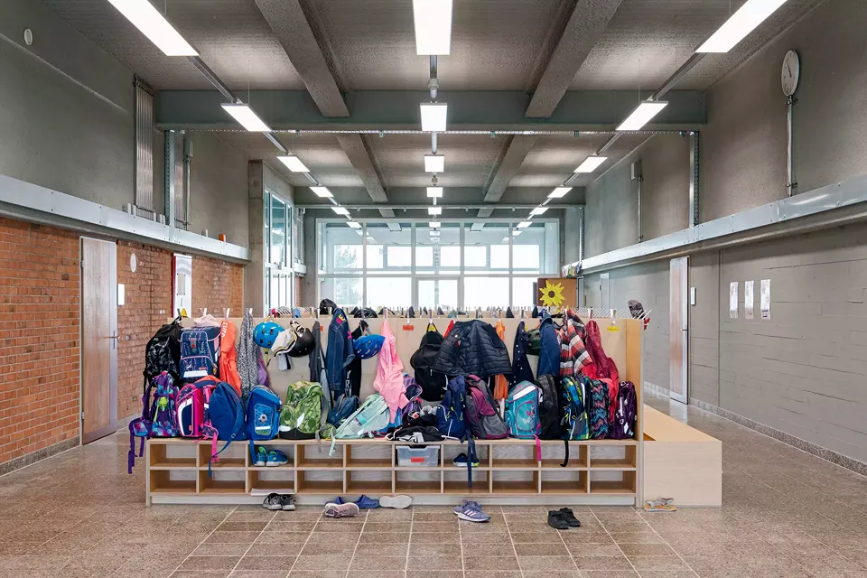 Mäandrierende Garderoben, die für alle Schüler:innen ein eigenes Fach für Schulmaterial bieten