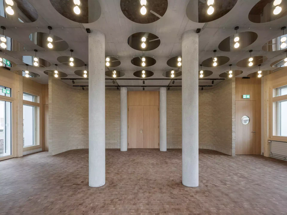 Innenansicht des Foyers im Erdgeschoss mit geschwungener Lehmsteinwand.