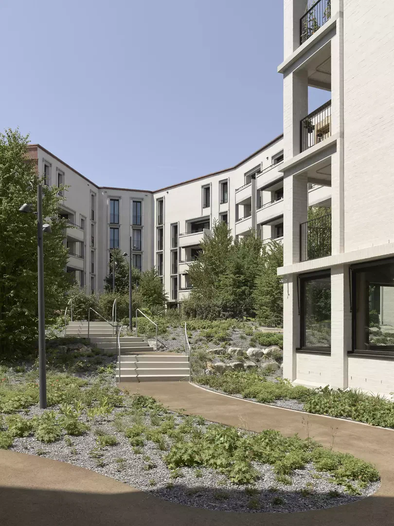 À l’extérieur, le lotissement se présente  dans des tons rouges chauds,  tandis que les cours intérieures sont dominées par des tons blancs cassés.