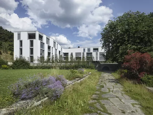 Das neue Gebäude nimmt den Platz der ehemaligen Gärtnerei ein. Eine kleines Wäldchen trennt das Baufeld vom Hauptteil des Parks und rahmt als Baumkulisse das Gebäude.