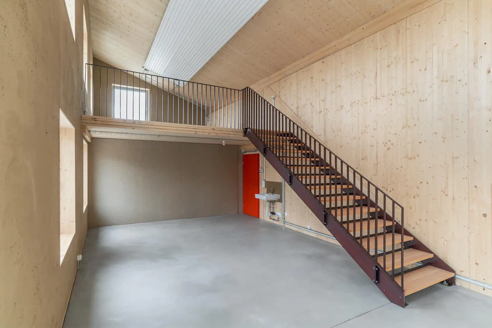 Intérieur avec vue sur les murs en crépi d'argile et l'escalier menant à la mezzanine