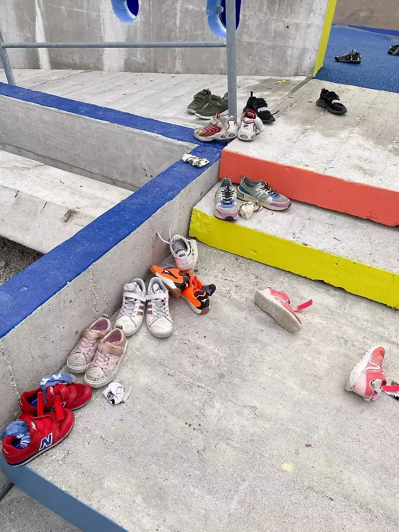 Un jour d'utilisation. Afin d'éviter de se mouiller les pieds, les enfants déposent leur chaussure à l'entrée. La couleur souligne les lignes de découpes de la structure béton