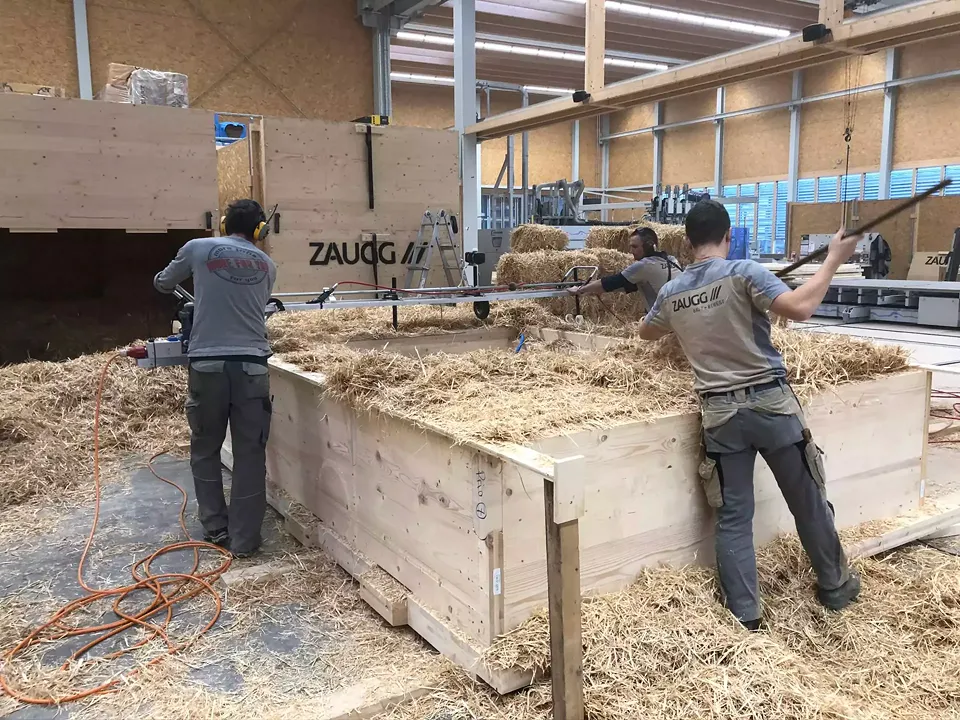 68 modules ont été préfabriqués par Zaugg  en Haute-Argovie bernoise. La paille n’a  pas été la seule à y être insérée dans. Le crépi intérieur et extérieur a également été appliqué  et les installations sanitaires et électriques ont été mises en place.