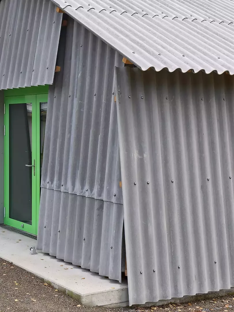 In seiner Gestalt erinnert, der mit Welleternit verkleidete Holzbau, an ein Festzelt eingekleidet in Stoff.