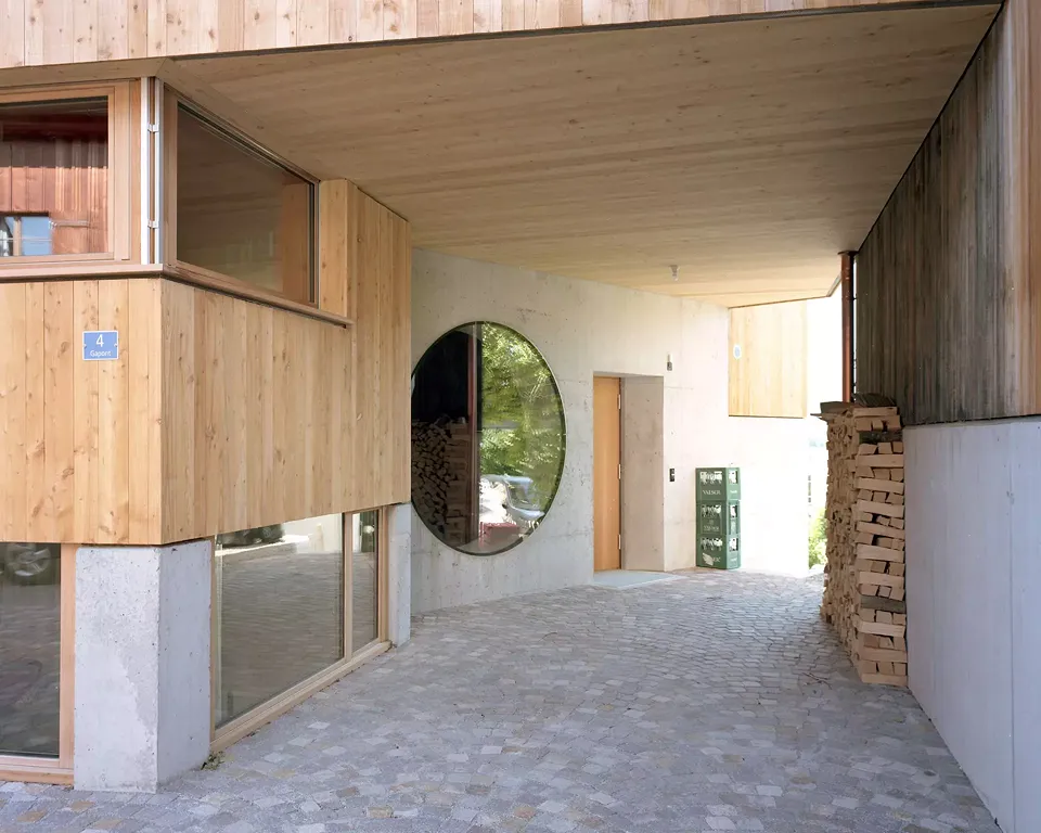 Der Durchgang zum Garten ist zugleich  ein überdachter Auto­­stellplatz und Vorzone  für den Eingang. Das Mondfenster neben  der Türe erlaubt einen Einblick ins Foyer.