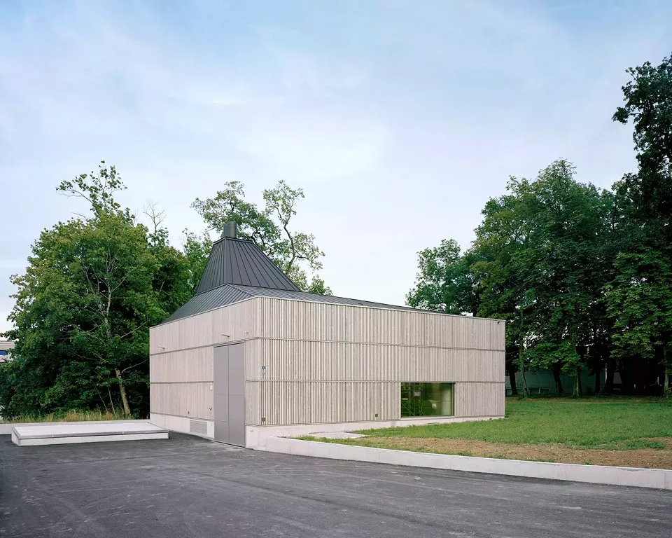 Durch die orthogonale Form und das Walmdach fügt sich der Bau perfekt im bebauten Kontext ein. Indem die Architekten das Gebäude abseits der Strasse in unmittelbarer Nähe der Baumbestände errichteten, konnten sie den Bau optimal in die Landschaft integr