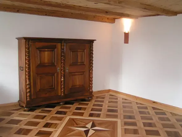 Wohnzimmer mit Tafelparkett, das in der eigenen Schreinerei restauriert und wieder fachmännisch verlegt wurde. Stern als Blickfang im Zentrum.