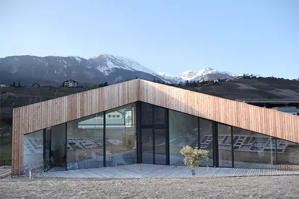 Vue depuis la terrasse surélevée et ombragée le long des arbres, offrant une vue sur tout le massif, la façade sud masquant les constructions imposantes voisines.