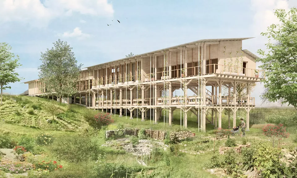 Das Gebäude im Sommer - Umgeben vom Permakulturgarten, der mit dem Gebäude verschmelzt und eine Symbiose eingeht.
