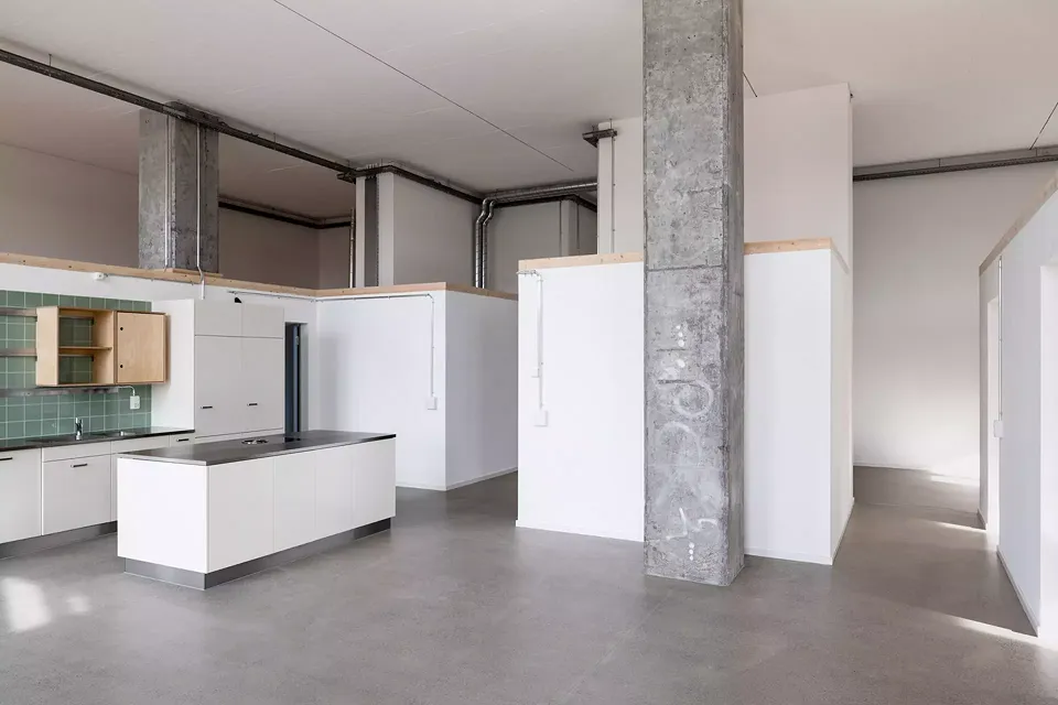 La hauteur des anciens espaces du dépôt n’était pas suffisante pour pouvoir les subdiviser  en deux étages. Les habitant·e·s peuvent néanmoins utiliser individuellement les surfaces disponibles  sur les cubes aménagés.
