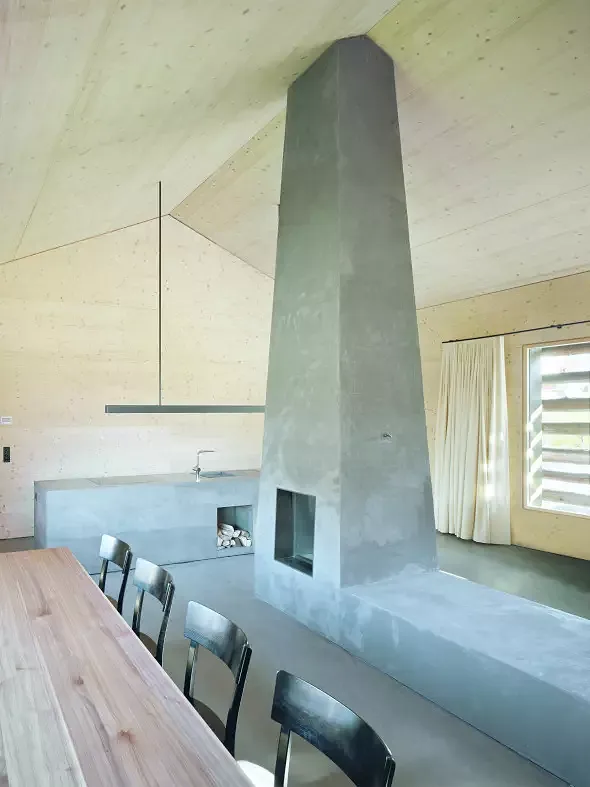 Der Wohnraum wird durch Küchenzeile und dem pyramidenförmige Kamin mit Sitzbank geprägt und zoniert.