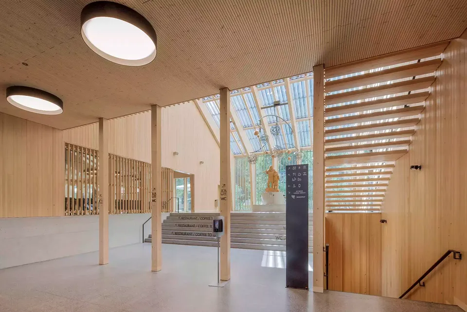 Grand foyer, vue depuis l’entrée en direction ouest. Vue sur la galerie où trône la sculpture géante de Guillaume Tell. Tel  un podium, le socle en pierre intègre un escalier à six marches qui permet au niveau du couronnement de la digue.