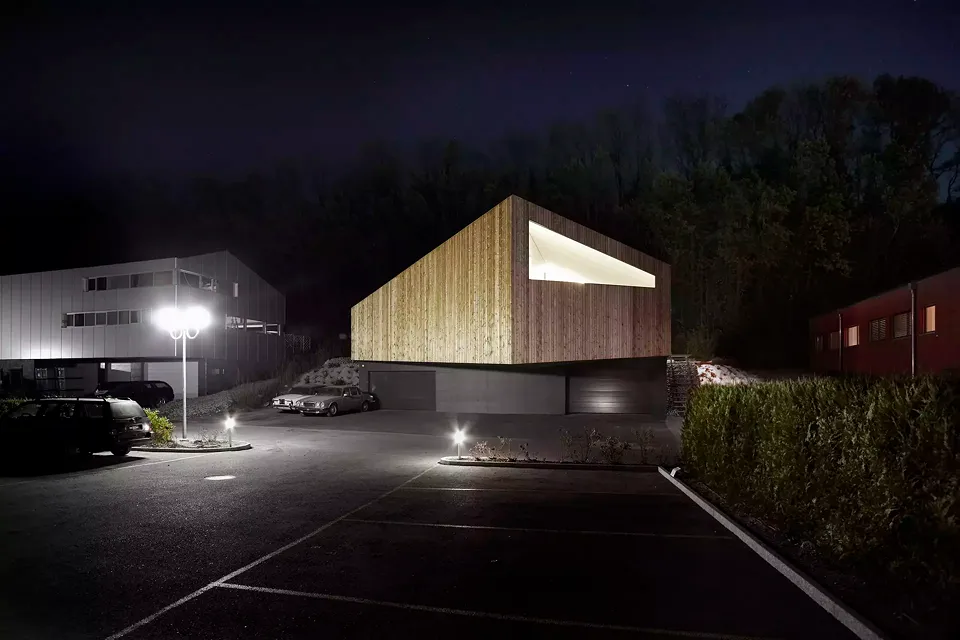 Vue nord: le volume en bois du logement se distingue clairement des garages en béton au niveau de la route