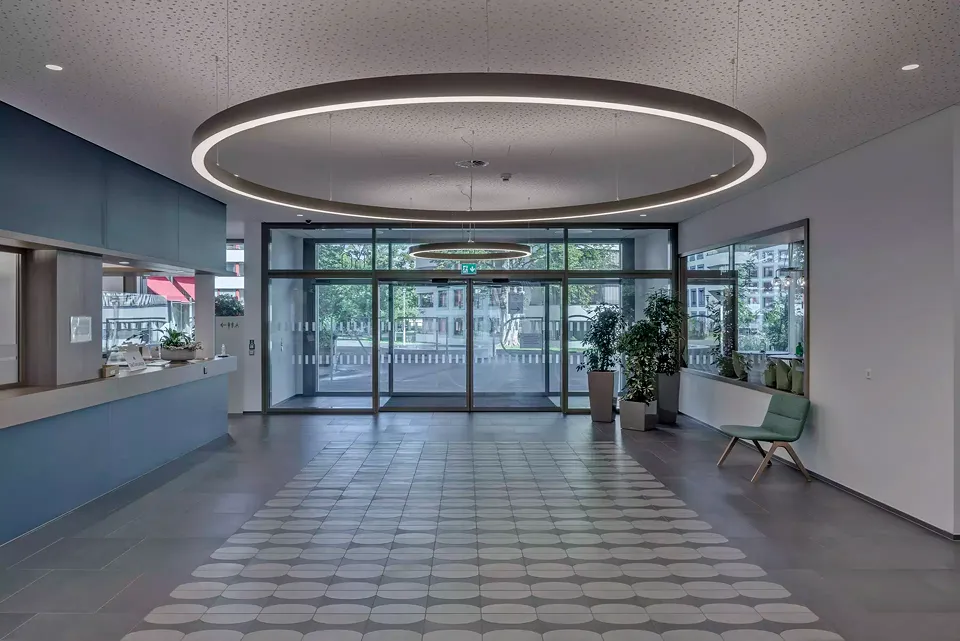 Au centre du bâtiment, le passage  ouvre sur le quartier. Il regroupe  le service la conciergerie, le cluster  de boîtes aux lettres et l’entrée du restaurant.