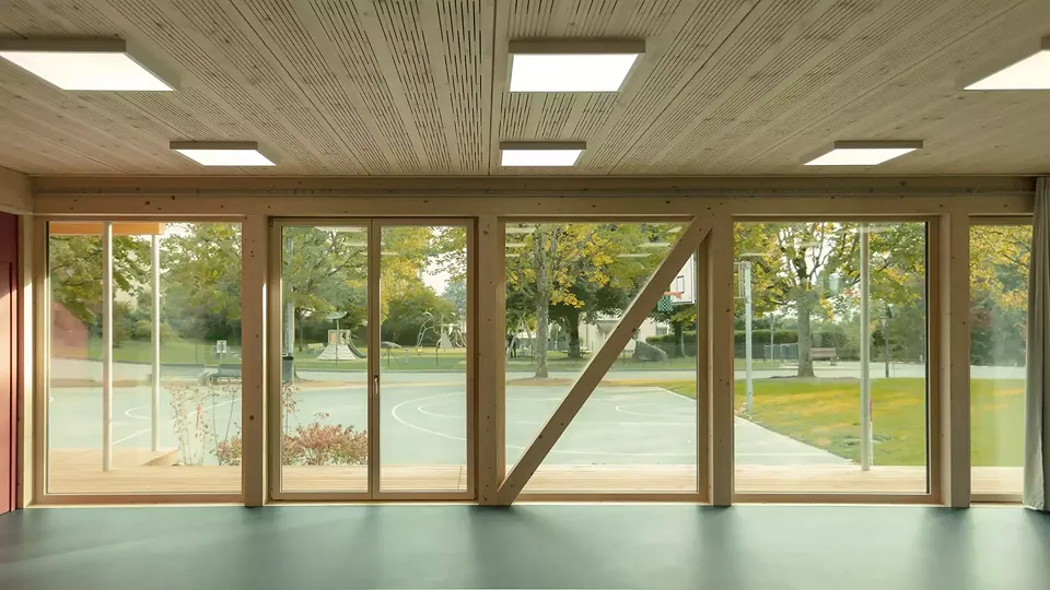 Vue vers le terrain de basket : ouverture des salles de classe sur le paysage environnant