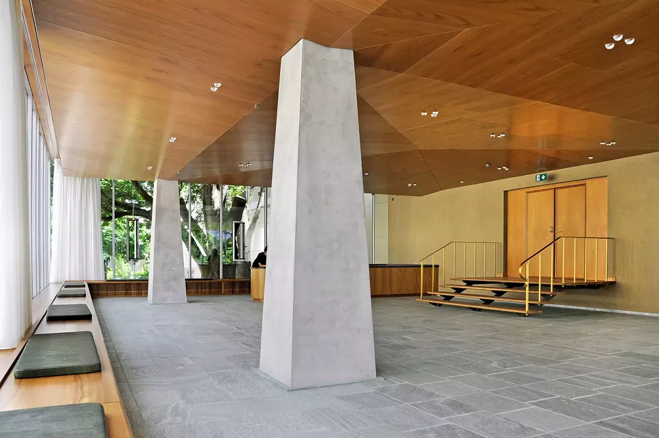 Vue du foyer et de  l’escalier menant à la  salle. Le vitrage prolongé vers le haut derrière  un talon du faux plafond est visible sur la gauche  de l’image.