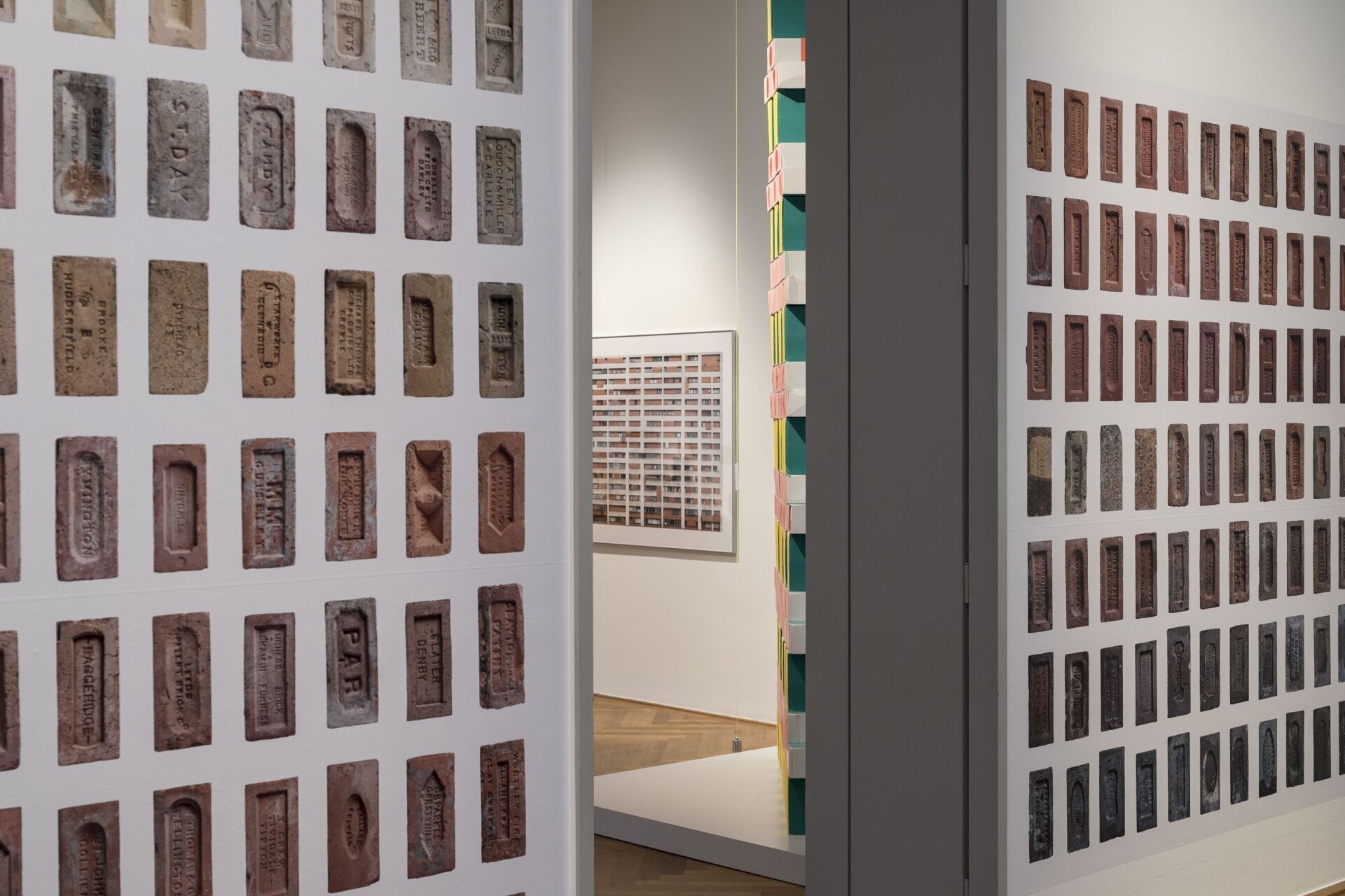 Ziegelstempel erzählen von ihrer Herkunft – Fotografien aus Patrick Frys Brick Index säumen den Durchgang der Ausstellung. Michael Lio