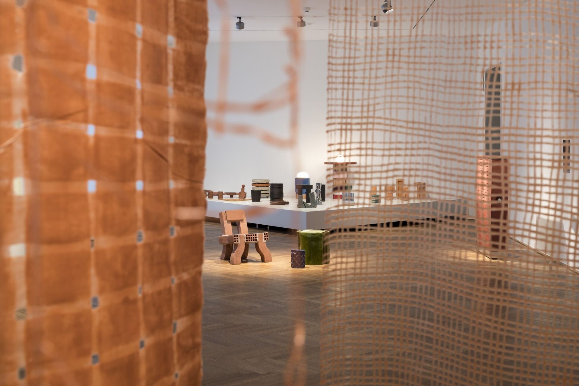 Blick durch die durchlässigen Elemente der Ausstellungsgestaltung auf die präsentierten Backsteinobjekte. | Foto: Michael Lio. Blick durch die durchlässigen Elemente der Ausstellungsgestaltung auf die präsentierten Backsteinobjekte. | Foto: Michael Lio.