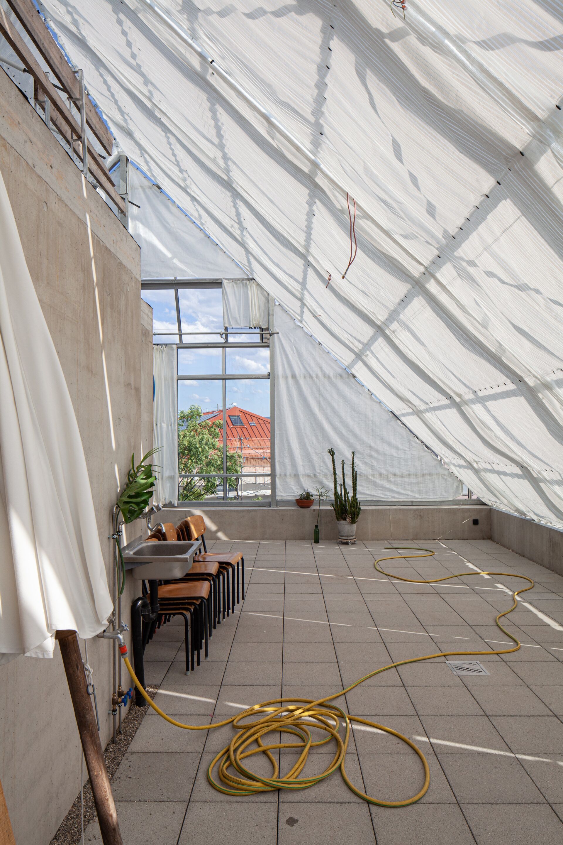 En hiver, les plantes en bacs peuvent être transportées des balcons vers la serre sur le toit. De plus, elle sert de salle multifonctionnelle aux habitant·e·s. | Photo: Christian Kahl L’idée d’une toiture terrasse couverte et accessible à tous les habitants est née en cours de planification. Elle renvoie l’image du pont promenade d’un bateau. 