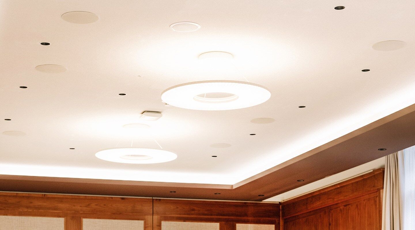 Les spots, le point d'accès WLAN et les haut-parleurs sont intégrés de manière professionnelle dans le plafond rafraîchissant et chauffant recouvert d'un enduit acoustique projeté sans joints | Photo © monoplan Les spots, le point d'accès WLAN et les haut-parleurs sont intégrés de manière professionnelle dans le plafond rafraîchissant et chauffant recouvert d'un enduit acoustique projeté sans joints | Photo © monoplan