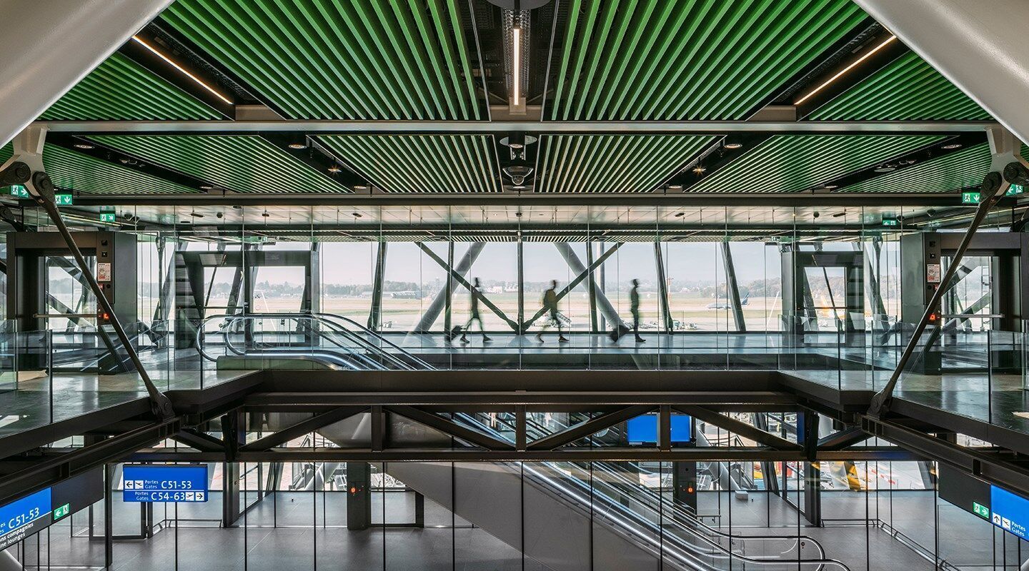 Les baffles perforés et activés des deux côtés fournissent une puissance de refroidissement élevée et constante et l'isolation acoustique intégrée optimise en même temps l'acoustique de la pièce dans le vaste terminal très fréquenté de l'aéroport de Genève. © Photo: Joas Souza (joas.co.uk) Les baffles perforés et activés des deux côtés fournissent une puissance de refroidissement élevée et constante et l'isolation acoustique intégrée optimise en même temps l'acoustique de la pièce dans le vaste terminal très fréquenté de l'aéroport de Genève. © Photo: Joas Souza (joas.co.uk)